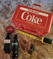 Group shot showing carrier, flashlight, door handle, miniature six-packs, loose bottles, and measuring tape