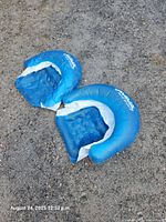 Two blue Aqua inflatable chairs on gravel