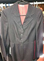 Front view of black Harry Hall riding jacket on hanger showing three-button closure and lapels