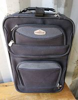 Front view of black Cambridge softside wheeled suitcase showing brand badge and zip pockets