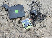Top view of Xbox console, two loose controllers, sealed controller pack, tangled cables