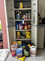 Front view of cabinet with four shelves of assorted chemical containers and tools, plus additional items arranged on floor