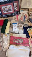Group shot showing cross-stitch kits, yarn, patterns, thread, knitting needles, Velcro and quilting board
