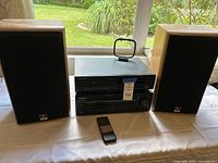 Front view of CD player and receiver stacked between bookshelf speakers; remote in foreground