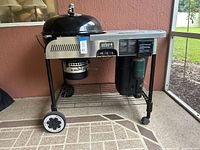 Front angled view of Weber Performer grill showing kettle, side table, propane cylinder and lower shelf