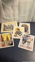 Five Norman Rockwell lithograph prints laid out on table