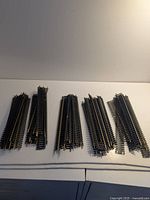 Five stacks of straight model train track pieces