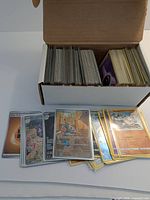 open box filled with rows of Pokémon cards, some holographic cards spread in front