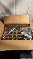 open box showing grid of glass bottles and extra caps