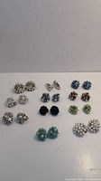 Group shot showing 11 pairs of bead cluster clip-on earrings