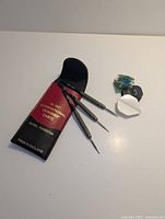 Full set laid out: three darts, extra flights, pouch