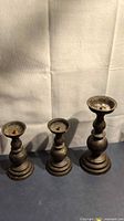 Three graduated brass candlesticks front view showing size comparison and overall condition