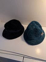Black and teal fur hats side by side