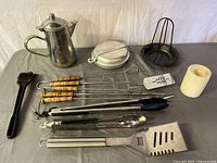 All items laid out on table: coffee pot, mess kit, utensils, roaster, candle