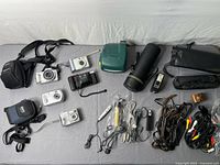Full layout showing all cameras, lens case, flash, microphone, remotes, bags, straps and cords
