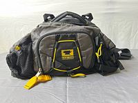 Front view showing logo patch, zip compartments, mesh side pockets, yellow accents