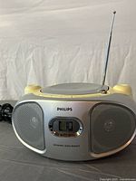 Front view of Philips AZ102S showing speaker grilles, display, Dynamic Bass Boost label, attached power cord