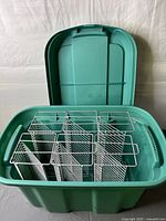 green plastic tote open showing six stacked white wire CD racks