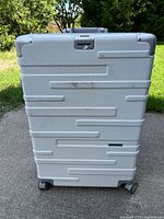 Front view of silver hard-shell suitcase with grooves and wheels