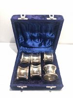 open blue velvet box holding six silver-tone napkin rings