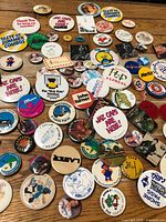 Overhead view of entire assortment of pin-back buttons spread on wooden surface