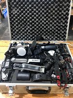Open aluminum case showing cameras, lenses, accessories