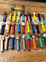 All 32 Pez dispensers laid out in four rows on floor