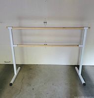 Full view of double ballet barre showing wood dowels and white metal frame