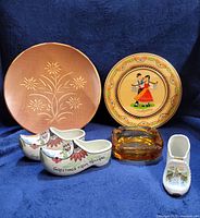 All lot items together: two wood plates, amber ashtray, three ceramic clogs
