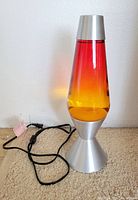 Full view of lava lamp showing base, cap, liquid color gradient and power cord
