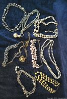 Group shot of all nine necklaces arranged on dark fabric