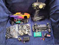 Full lot showing assembled car, remote, spare chassis, three batteries and bags of parts