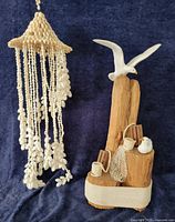 Driftwood sculpture with three ceramic seagulls beside cascading shell chandelier