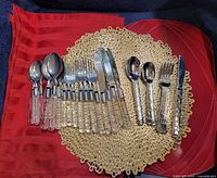 Flatware sets displayed on red cloth and gold vinyl placemats