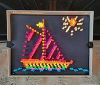 Front view of Lite-Brite illuminated with completed sailboat design