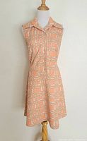 Front view of orange and white sleeveless collared dress on mannequin