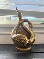 Front view of brass twin-swan wall planter showing overall design, finish and vessel opening.