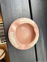 Top view showing pink ashtray with white floral relief and three rests