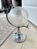 Full view of chrome globe liquor dispenser showing globe, spigot, and pedestal base
