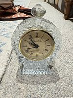 Front view showing full glass clock, finial, gold bezel, dial