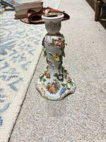 Full view of porcelain candlestick showing floral appliqués and gilt accents