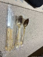 Packaged knives and spoons showing ornate gold handles