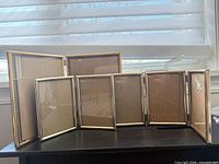 Front view of hinged gold-tone picture frame fully extended showing all six glass openings