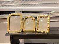 Front view of three gold ornate frames on shelf