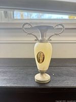 Full view of alabaster vase showing body, metal handles, neck, base, and label