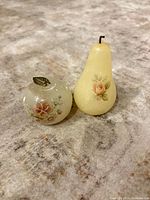 Front view of apple and pear paperweights showing color, floral decals, metal stems