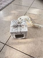 Porcelain ornament side view showing bow, silver accents, ribbon hanger