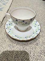 Front view of teacup on saucer showing floral pattern and gold trim