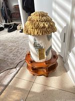 Full lamp assembled showing ceramic cottage body, thatch roof, wood base