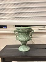 Front view of seafoam green ceramic planter showing scrollwork and handles